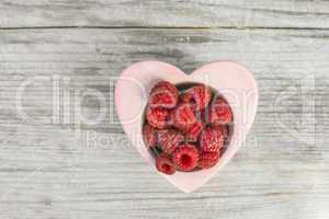 Raspberries in a bowl on wood