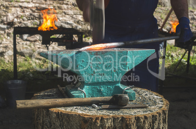 Blacksmith forges iron on anvil