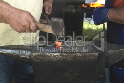 Blacksmith forges iron on anvil