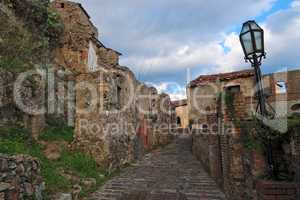 Paved medieval street with ruined house in Savoca village, Sicily, Italy