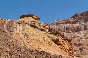 Weathered orange rock on top of dune in desert canyon