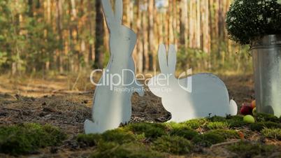 composition on the ground in the forest of candles, cardboard rabbits