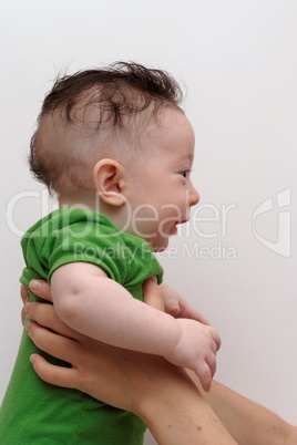 Cute smiling baby held by his mother profile view