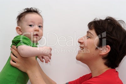 Cute baby held by his smiling mother looks toward the camera
