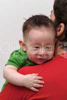Rear view of cute smiling baby boy  looking over mother shoulder