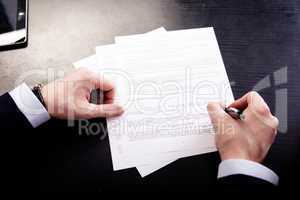 Image of human hand with pen over documents at workplace