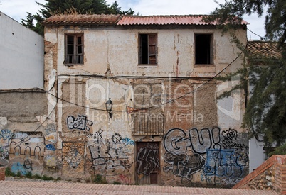 Facade of a deserted house with bricked-up windows and graffiti