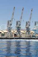 Row of cranes and their reflections in the sea in Eilat harbor, Israel