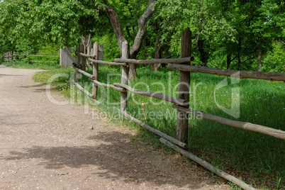 Rural path enclosed with lath fence at summer