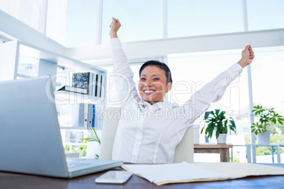 Businesswoman cheering behind laptop computer