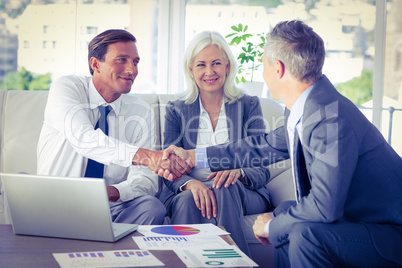 Business people shake hands on couch