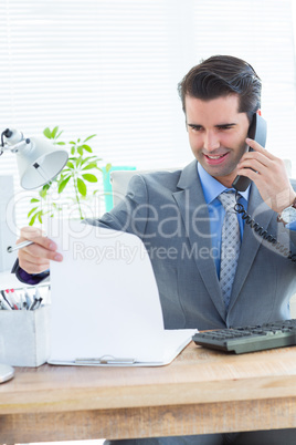 Happy businessman phoning and looking note