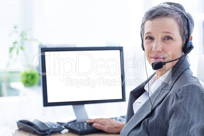Smiling businesswoman phoning and using computer