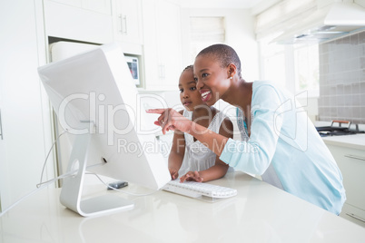 Happy smiling mother with her daughter using computer