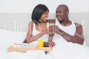Pretty couple taking breakfast in bed together