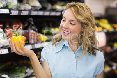 Smiling blonde woman having a vegetable on her hand
