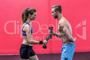 A muscular couple lifting dumbbells