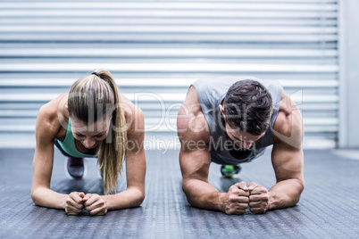 Muscular couple doing planking exercises