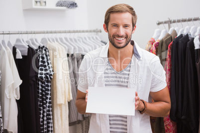 Portrait of smiling man holding blank sign and looking at camera