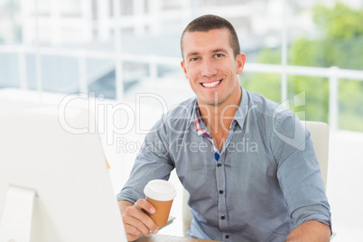 Smiling creative businessman holding a mug of coffee