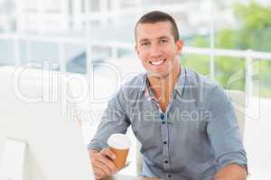 Smiling creative businessman holding a mug of coffee