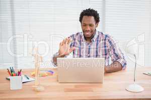Young businessman waves at his laptop