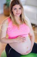 Pregnant woman touching her belly on exercise ball