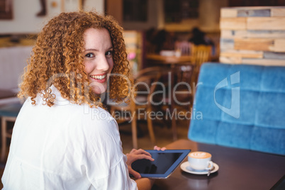 Pretty girl using a small tablet at table