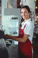 Pretty barista looking at camera and using the coffee machine