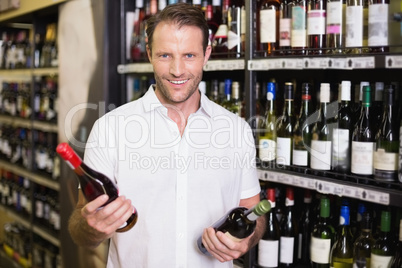 Portrait of a smiling handsome showing a wine bottle