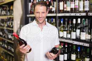 Portrait of a smiling handsome showing a wine bottle