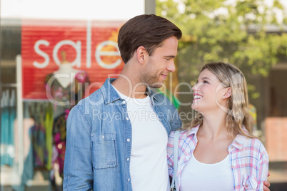 happy couple standing in front of a SALE sign