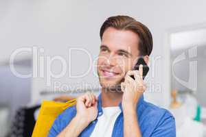 A smiling man with shopping bags calling