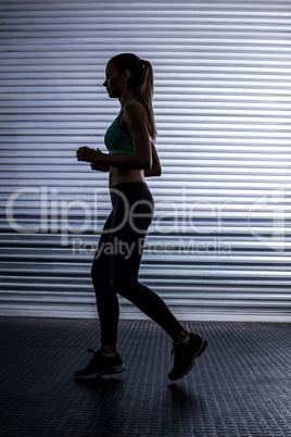 Muscular woman running in exercise room