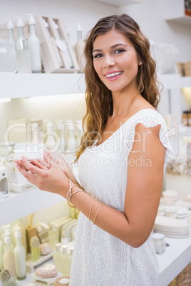 Portrait of smiling woman testing moisturizer and looking at cam