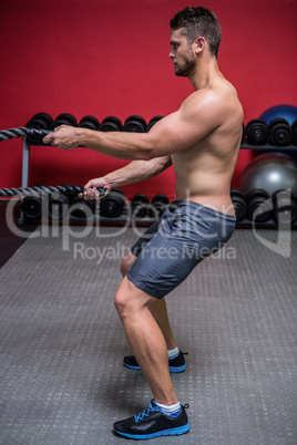 Muscular man exercising with rope