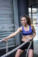 Muscular woman exercising with rope