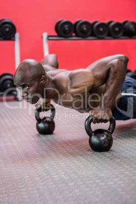 Muscular man doing push-ups with kettlebells