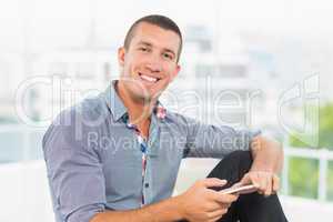 Smiling businessman sending a text message