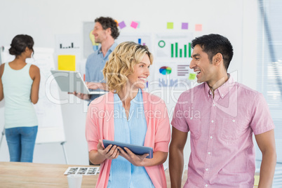 Casual businesspeople using digital tablet with colleagues behi