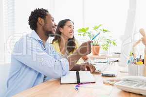 Smiling colleagues speaking together at desk