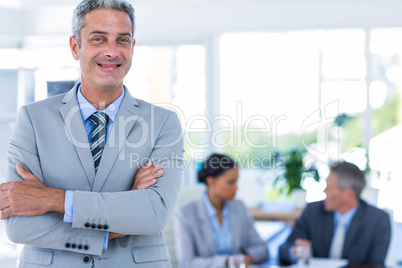 Businessman looking at camera with his colleagues behind him