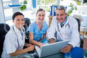 Doctors and nurse looking at laptop and smiling at camera