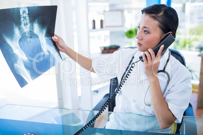 Doctor looking X-rays while having phone call