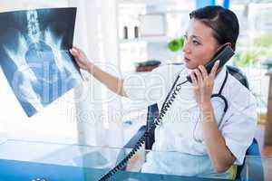 Doctor looking X-rays while having phone call