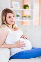 Pregnant woman touching her belly on the couch