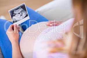 Pregnant woman looking at ultrasound scans and touching her bell
