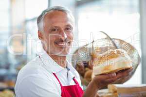 Waiter looking at camera and holding freshly baked bread