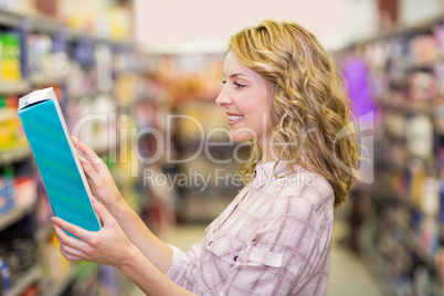 Side view of smiling pretty blonde woman reading a book