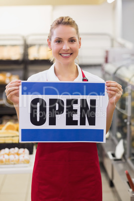 Portrait of a smiling blonde woman holding a sign